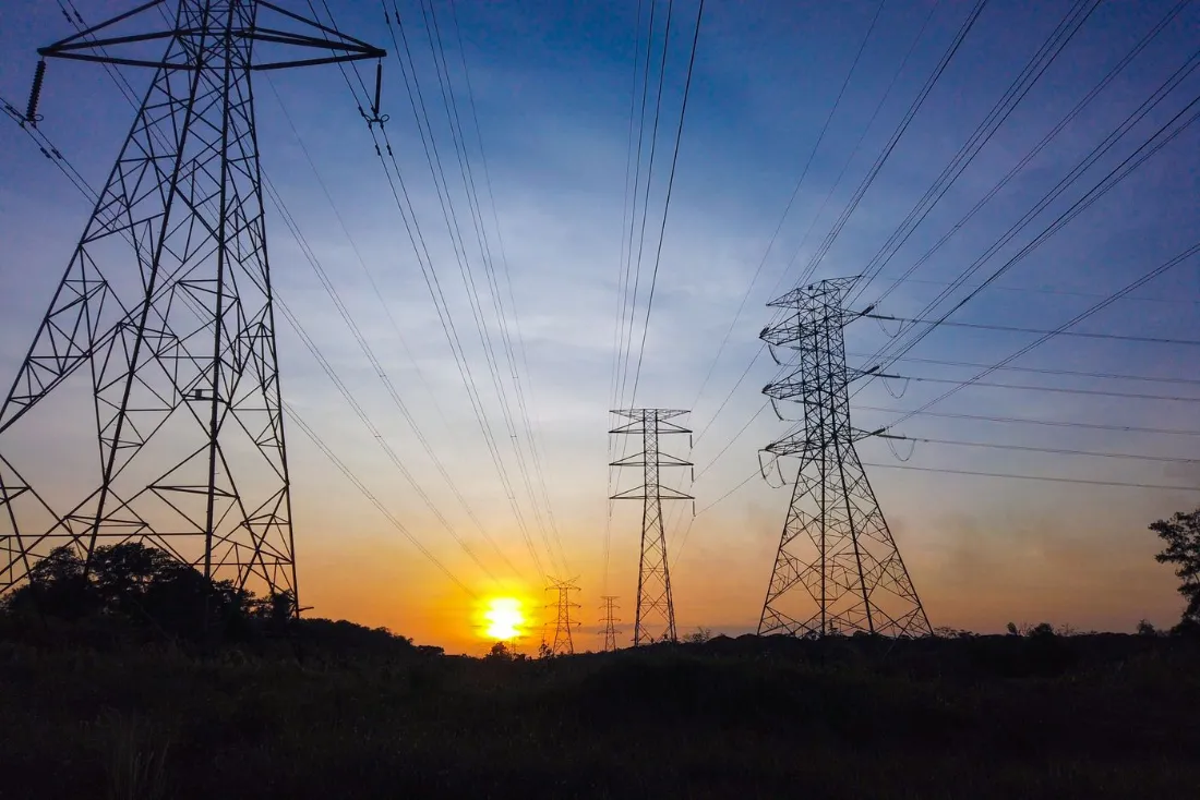 Torres y líneas de alta tensión al atardecer, la red por la que una comercializadora suministra electricidad a sus clientes